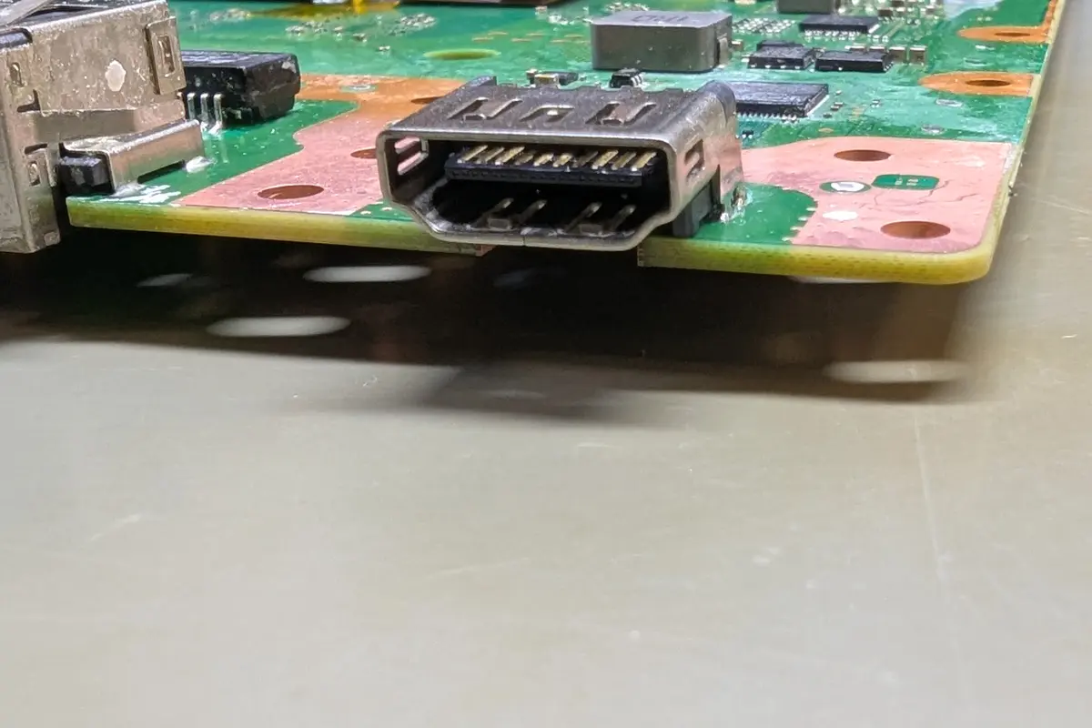 Close-up of a repaired HDMI port on a gaming console circuit board