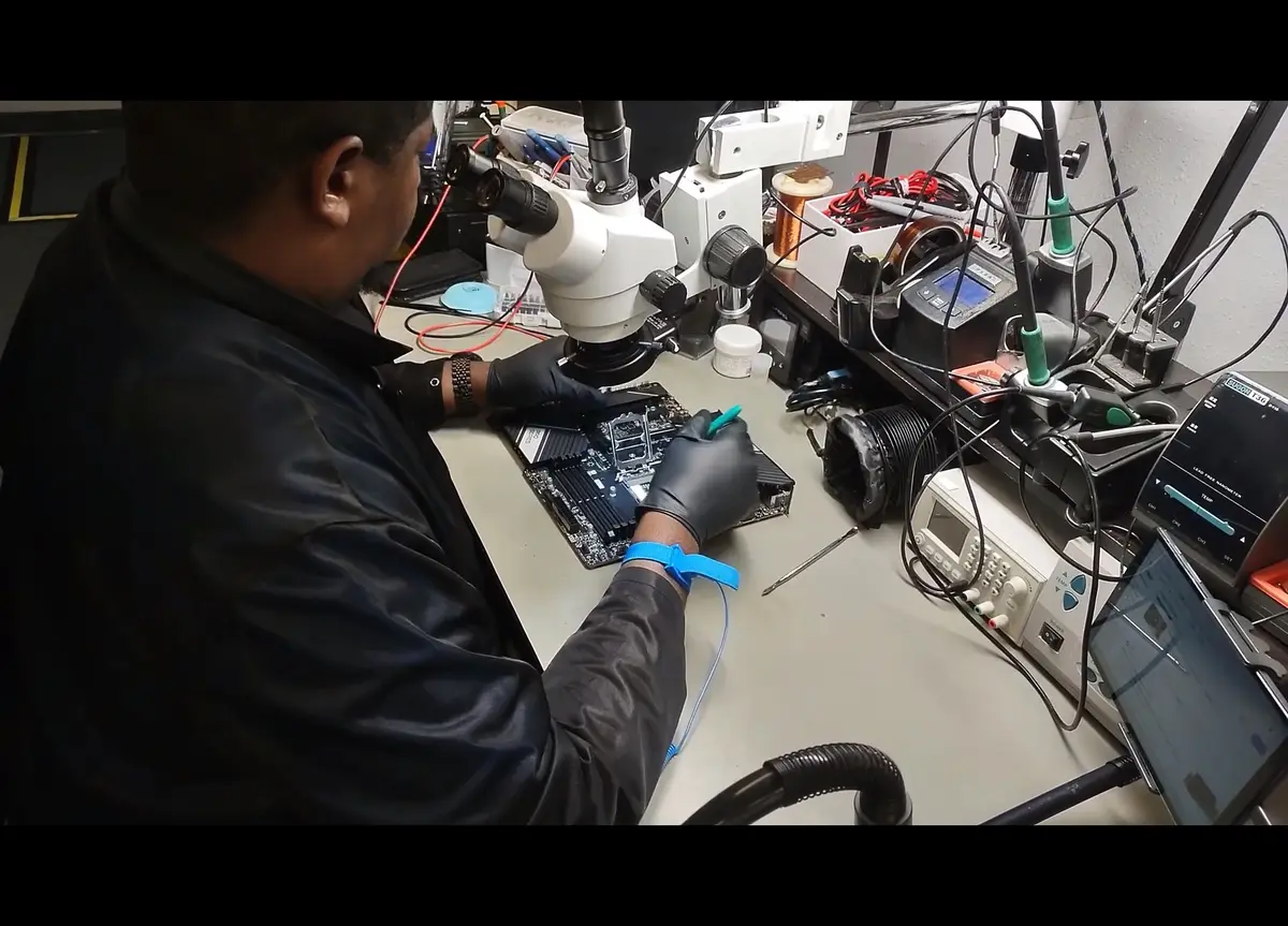 Technician inspecting a motherboard at the Zidra repair workstation