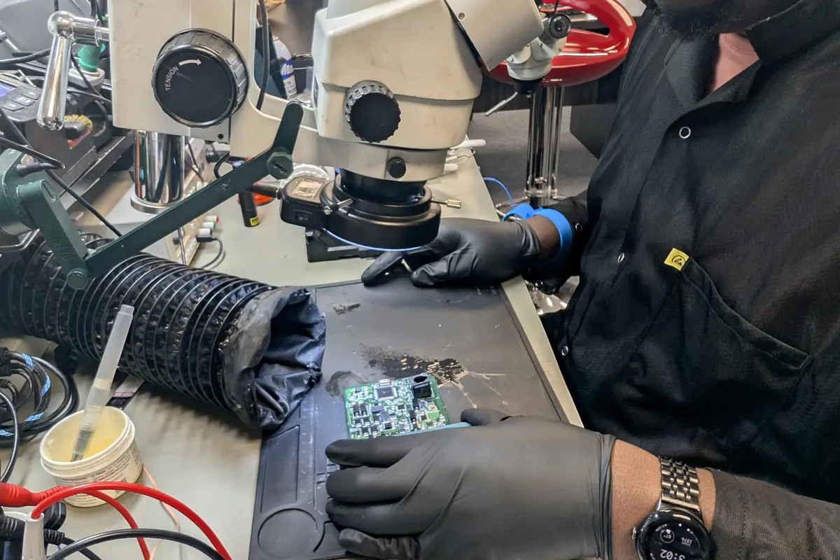 Zidra technician performing micro-soldering under a stereo microscope